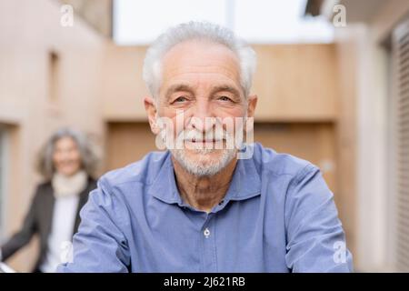 Lächelnder älterer Mann mit weißen Haaren vor der Frau Stockfoto