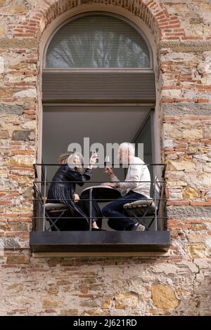 Ein glückliches Seniorenpaar mit Weingläsern, die auf dem Balkon im Boutique-Hotel saßen Stockfoto