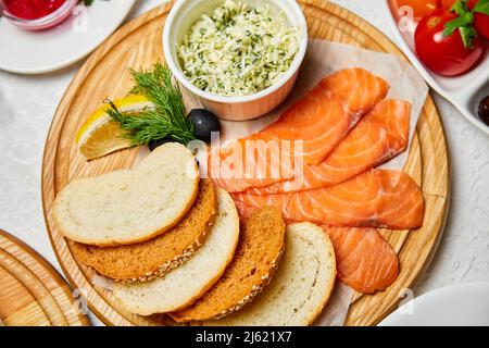 Leicht gesalzener Lachs mit Käse und Brotscheiben auf einem Holzbrett Stockfoto