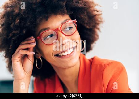 Lächelnde Geschäftsfrau mit Afro-Frisur und Brillen Stockfoto