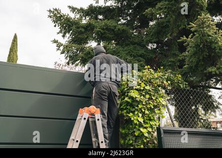 Bauarbeiter, der auf einer Leiter steht und auf der Baustelle arbeitet Stockfoto