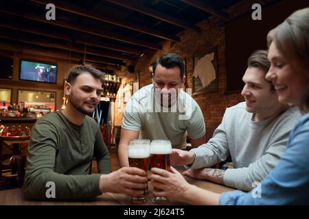 Freunde treffen sich in einem Pub und klirrende Biergläser Stockfoto
