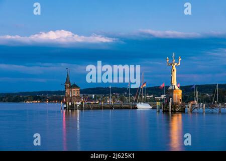 Deutschland, Baden-Württemberg, Konstanz, Hafen am Ufer des Bodensees in der Abenddämmerung mit Leuchtturm und Statue von Imperia im Hintergrund Stockfoto