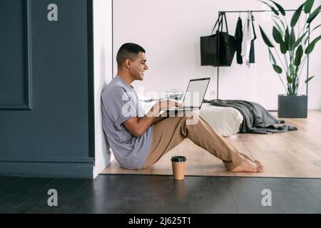 Lächelnder Mann mit Laptop, der zu Hause sitzt Stockfoto