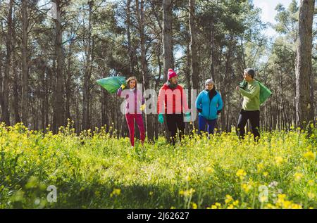 Freiwillige mit Mülltüten, die an sonnigen Tagen im Wald spazieren Stockfoto