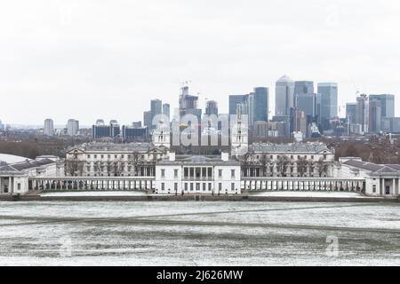 Blick auf das Queens House und Canary Wharf vom Greenwich Park in London im Winterschnee Stockfoto