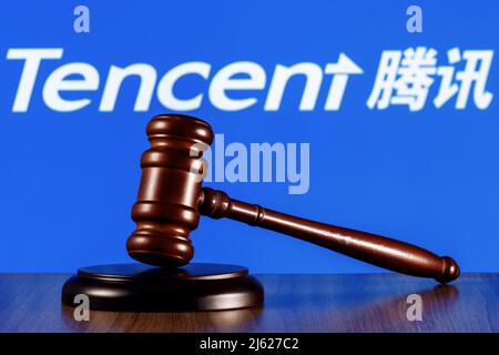 Gavel auf dem Tisch vor dem Hintergrund des Tencent Firmenlogos. Das Konzept des Trials. Stockfoto