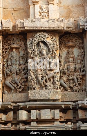 Ein hinduistischer Gott und eine Göttin unter den Schnitzereien am Hoysaleswara Tempel in Halebid, Karnataka, Indien Stockfoto