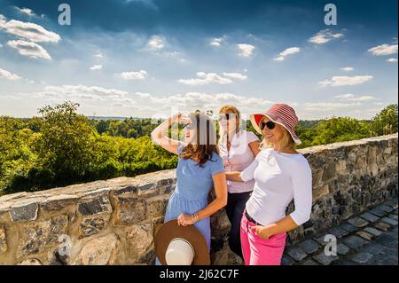 Drei Frauen sitzen auf der Steinmauer und genießen das Land Stockfoto