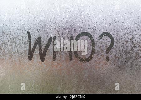 Die Quaestion, die mit dem Finger auf Nacht nasses Glas mit verschwommenem Licht im Hintergrund geschrieben Stockfoto