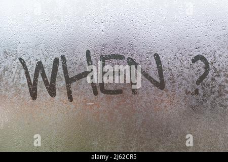 Die Quaestion, wenn mit dem Finger auf Nacht nass Glas mit verschwommenem Licht im Hintergrund geschrieben Stockfoto