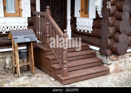 Hölzerne Veranda mit Stufen und einer Tür zu einer Blockhütte. Dorf beherbergt Architektur Stockfoto