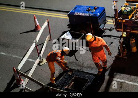 Nächtliche Straßenarbeiten, bei der eine kaputte Schachtabdeckung auf der Straße repariert wurde, in Hertfordshire, Großbritannien. Von den Auftragnehmern Cappagh im Auftrag von Thames Water durchgeführte Arbeiten. Foto: David Levenson/Alamy Stockfoto