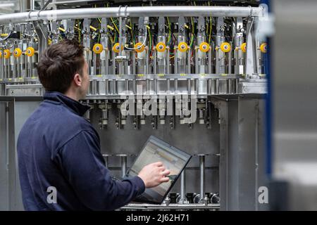 Neutraubling, Deutschland. 25. April 2022. Ein Mitarbeiter der Krones AG arbeitet an einer Abfüllanlage in der Produktion. Quelle: Armin Weigel/dpa/Alamy Live News Stockfoto