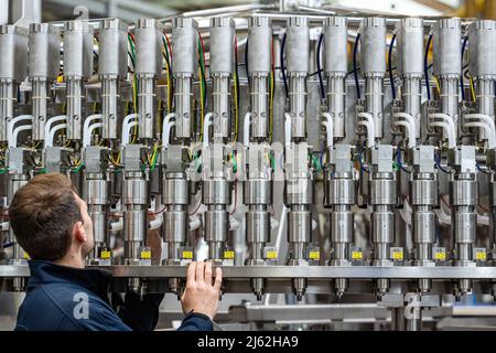 Neutraubling, Deutschland. 25. April 2022. Ein Mitarbeiter der Krones AG arbeitet an einer Abfüllanlage in der Produktion. Quelle: Armin Weigel/dpa/Alamy Live News Stockfoto