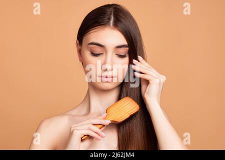 Schöne Frau kämmt ihre Haare mit Holzbürste Stockfoto