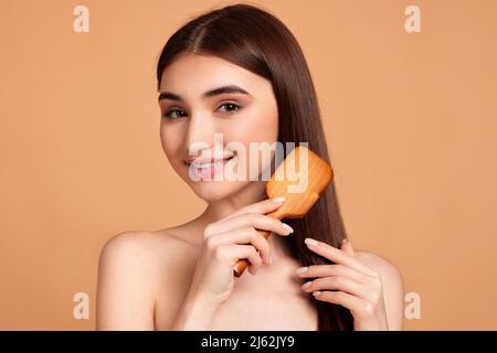 Schöne Frau kämmt ihre Haare mit Holzbürste Stockfoto