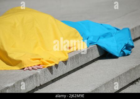 Berlin: Deutschland, 27. April 2022, 27. April 2022, Berlin: Auf der Terrasse vor der Neuen Nationalgalerie findet die Performance '254' der ukrainischen Künstlerin Maria Kulikovska statt, die sich mit einer ukrainischen Flagge bedeckt hat. Krieg und seine Folgen sind zentrale Themen im Werk des auf der Krim geborenen Künstlers. Die Aufführung ist eine Nachstellung einer nicht sanktionierten Aktion im Eremitage-Museum in Sankt Petersburg, Russland, im Jahr 2014, nach der Kulikovska kurzzeitig verhaftet wurde. Der Titel „254“ bezieht sich auf die Nummer, die sie nach der Annexion der Krim durch die Flucht nach Kiew erhalten hat, die als Refu registriert wurde Stockfoto