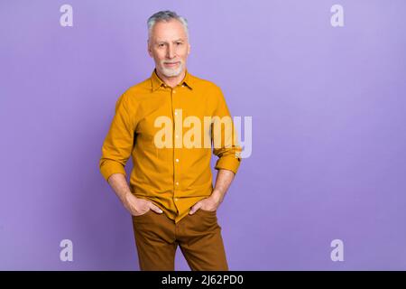 Foto von kühlen älteren grauen Frisur Mann tragen gelbes Hemd isoliert auf lila Hintergrund Stockfoto