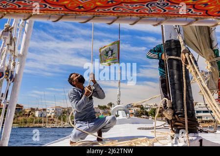 Sichere Fahrt auf dem traditionellen Felucca-Segelboot auf dem nil, während die Besatzung Gesichtsmasken trägt Stockfoto