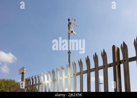 Sicherheitskameras und Stahl haben die Sicherheitszäune vor einem strahlend blauen Himmel angestachelt Stockfoto