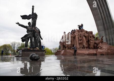 Ukraine. Kiew, 26. April 2022, Arbeiter demontieren das sowjetische Gewerkschaftsdenkmal, das die ukrainisch-russische Freundschaft symbolisiert, weil Russland weiterhin in die Ukraine einmarschiert. Am 25. April 2022 kündigte der Bürgermeister von Kiew, Vitali Klitschko, die Entfernung des sowjetischen Unionsdenkmals in Zentral-Kiew an. Dieses Denkmal wurde 1982 als Symbol der Wiedervereinigung der Ukraine und Russlands während der Sowjetzeit errichtet. Die Statue von zwei Männern mit einer Medaille stellt den Orden der Freundschaft der Völker der Sowjetunion dar, während der regenbogenartige Bogen den Namen „Volksfreundschaftsbogen“ nennt. Außerdem einige Straßen li Stockfoto