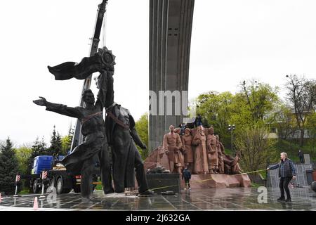 Ukraine. Kiew, 26. April 2022, Arbeiter demontieren das sowjetische Gewerkschaftsdenkmal, das die ukrainisch-russische Freundschaft symbolisiert, weil Russland weiterhin in die Ukraine einmarschiert. Am 25. April 2022 kündigte der Bürgermeister von Kiew, Vitali Klitschko, die Entfernung des sowjetischen Unionsdenkmals in Zentral-Kiew an. Dieses Denkmal wurde 1982 als Symbol der Wiedervereinigung der Ukraine und Russlands während der Sowjetzeit errichtet. Die Statue von zwei Männern mit einer Medaille stellt den Orden der Freundschaft der Völker der Sowjetunion dar, während der regenbogenartige Bogen den Namen „Volksfreundschaftsbogen“ nennt. Außerdem einige Straßen li Stockfoto