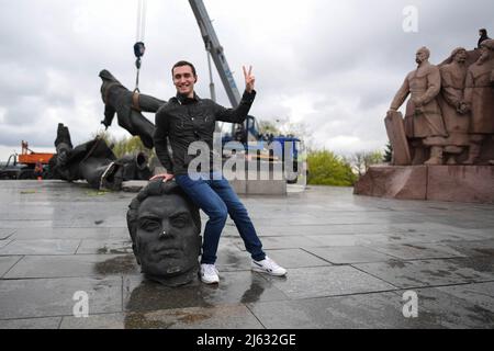 Ukraine. Kiew, 26. April 2022, Ein Mann posiert für Fotos mit dem demontierten Denkmal der Sowjetunion. Am 25. April 2022 kündigte der Bürgermeister von Kiew, Vitali Klitschko, die Entfernung des sowjetischen Unionsdenkmals in Zentral-Kiew an. Dieses Denkmal wurde 1982 als Symbol der Wiedervereinigung der Ukraine und Russlands während der Sowjetzeit errichtet. Kredit: SOPA Images Limited/Alamy Live Nachrichten Stockfoto