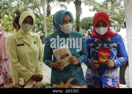 Madiun, Ost-Java, Indonesien. 27. April 2022. Leiter des Madiun Regency Family Welfare Empowerment Team (TP PKK) Penta Lianawati Ahmad Dawami mit Madiun Branch Bhayangkari Chair Hanna Anton Prasetyo und ihren jeweiligen Führungsreihen beim Einkauf lokal verarbeiteter Lebensmittel- und Getränkeprodukte für Regency Micro, Kleine und mittlere Unternehmen (MSMEs) Madiun auf dem Basar Ramadhan 1443 Hijriyah/Th 2022, der im Madiun Regency Government Center (Puspem) stattfand (Bild: © Ajun Ally/Pacific Press via ZUMA Press Wire) Stockfoto