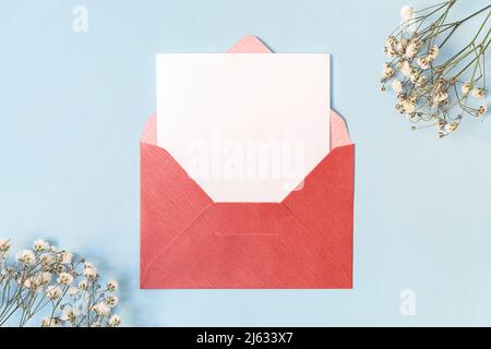 Zarte florale Komposition mit Umschlag und weißer leerer Karte auf hellblauem Hintergrund, Mockup, Kopierraum Stockfoto