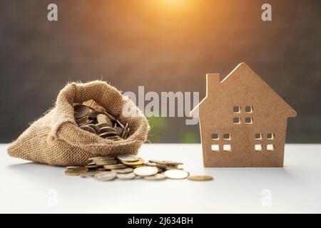 Ein Beutel mit Geld mit Holzhäusern. Das Konzept der Schulden für den Wohnungsbau. Hypothek. Immobilien, Immobiliensparen, Darlehen Marktkonzept. Risiken beim Kauf eines Hauses Stockfoto