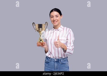 Mädchen Holding Trophy Zeigt Daumen Nach Oben Isoliert. Mädchenziele. Gewinner. Mädchen Schmillend. Trophäe in „Girl Hands“ Stockfoto