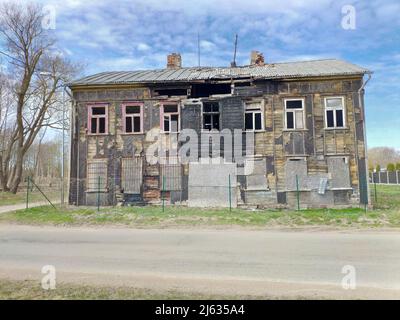 Altes halb verbranntes Holzhaus. Zerstörtes verlassene Haus mit blauem Himmel im Hintergrund Stockfoto