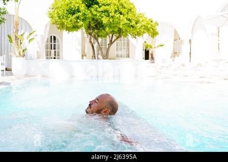 Mann, der sich im Pool im Urlaub in Riad, Marokko, entspannt Stockfoto