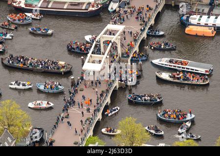 2022-04-27 13:20:12 AMSTERDAM - Luftaufnahme der Amstel gefüllt mit Booten und der mageren Brücke während des Königs Tages. Nach zwei Jahren, in denen der King's Day aufgrund der Corona-Pandemie in kleinem Umfang gefeiert werden musste, wird die Party in diesem Jahr wie gewohnt ausgelassen gefeiert. ANP BRAM VAN DE BIESES netherlands Out - belgium Out Credit: ANP/Alamy Live News Stockfoto