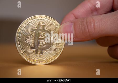 Hand hält virtuelle Währung Bitcoin. Nahaufnahme von goldenem Bitcoin. Stockfoto