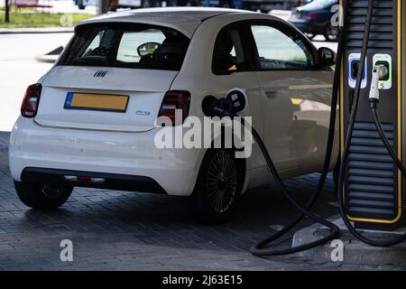 Elektrotransport. Laden eines Fiat 500E mit Strom an einer öffentlichen Ladestation im schnell wachsenden Kfz-Ladeletz von Fastned in den Niederlanden Stockfoto