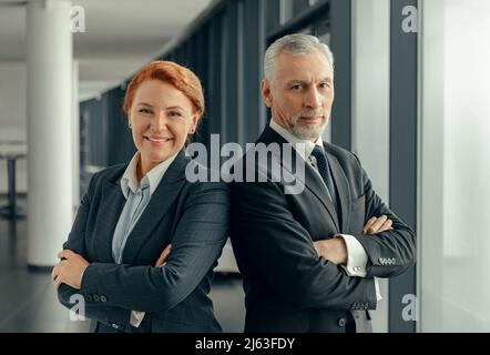 Porträt eines reifen Mannes und einer reifen Dame in schwarzen Business-Anzügen, die nebeneinander stehen Stockfoto