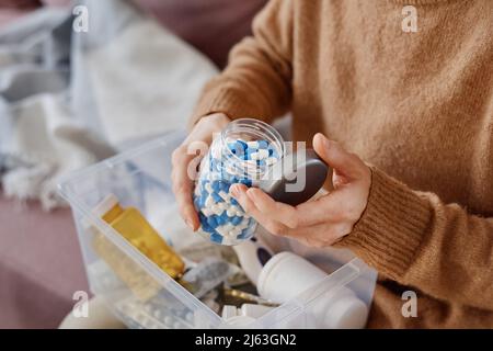 Mittellange Nahaufnahme einer Frau mit kalten Symptomen, die mit einem erste-Hilfe-Set auf dem Sofa sitzt Stockfoto