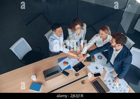 Glückliches erfolgreiches multirassisches Geschäftsteam, das Einheit mit ihren Händen zeigt Stockfoto