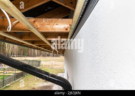 Gerüst mit drei Reihen von Holzlatten zur Befestigung der PVC-Soffit, sichtbare Kabel für die Beleuchtung. Stockfoto