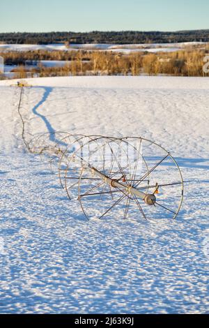 Ein Radlinen-Sprinkler auf einem Feld, im Winter mit Schnee auf dem Boden. Stockfoto