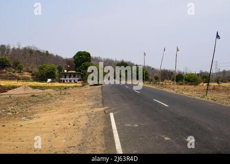Highway Road auf Ghat Berggebiet im Wald in madhya pradesh mit weißer Linie Markierung auf beiden Seiten der Straße und getrockneten Bäumen. Reifengeschäft in der Nähe des Motels On Stockfoto