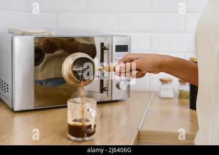 Nahaufnahme des Ausgießens von heißem Kaffee in die Tasse Stockfoto