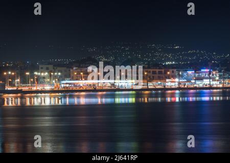 Paphos, Zypern - 2. April 2022: Nachtansicht der Stadt Paphos. Blick auf die Stadt Paphos vom Meer aus. Stockfoto