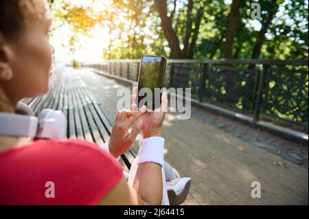 Fitness-App Sportlich-fulminante Frau, die nach dem Training im Freien auf das Smartphone mit leerem schwarzen Bildschirm zeigt und dabei eine Kopie vorführt Stockfoto