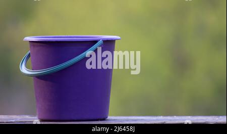 Leeren Sie den purpurnen Garteneimer aus nächster Nähe auf Holzbrettern. Stockfoto