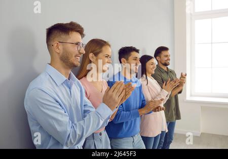 Eine Gruppe glücklicher junger Menschen applaudiert auf einer Geschäftskonferenz oder einem Teamtreffen. Stockfoto