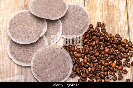 Draufsicht auf Kaffeepads und Kaffeebohnen auf einer rustikalen Holzoberfläche als Beispiel für verschiedene Kaffeerohprodukte. Flache Lay-Komposition Stockfoto