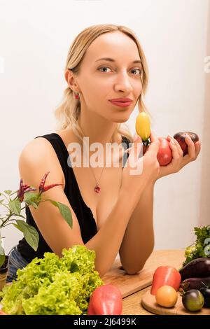 Junge Frau hält Tomaten in den Händen, während sie am Tisch sitzt Stockfoto